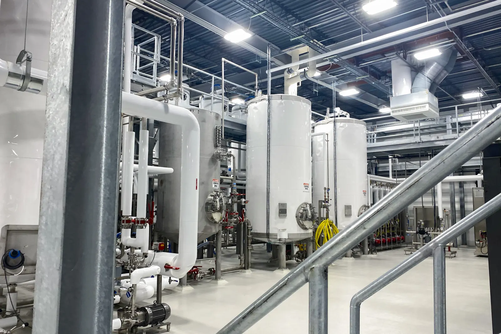 Two large white tanks for tagatose production in a plant, surrounded by other equipment.