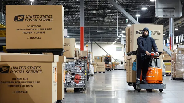 A U.S. Postal Service employee transports parcels for distribution inside a facility.