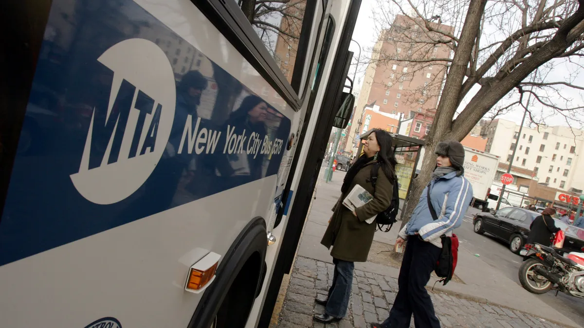 A photo of two people boarding a bus in New York City.