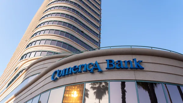 Comerica Bank signage is seen on the exterior of a curved stone and glass building