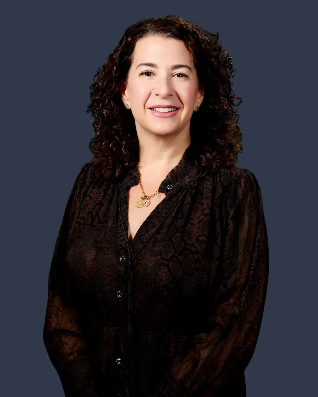 A person with long dark wavy hair and dark clothes.