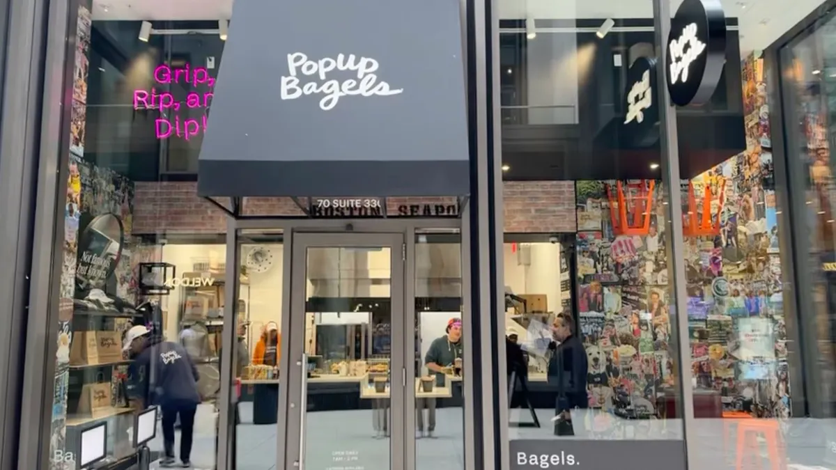 An image of a glass storefront with a sign that says "PopUp Bagels