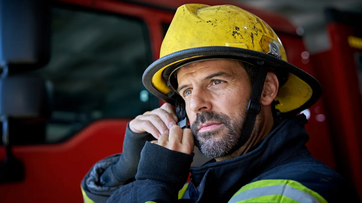 A firefighter in full gear standing inside in front of a fire truck