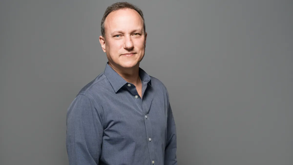 Jay Gaines is pictured for a professional headshot in front of a grey background.