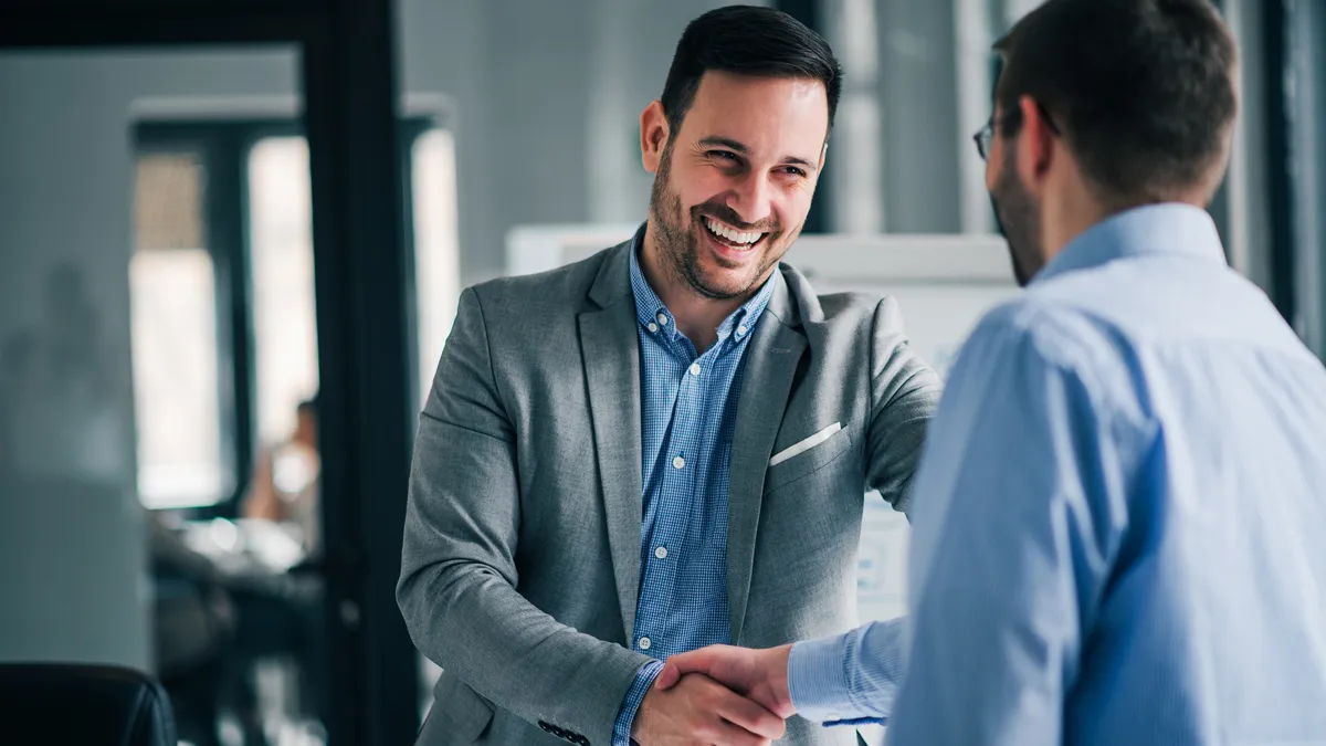 A new manager shakes the hand of an employee in the office