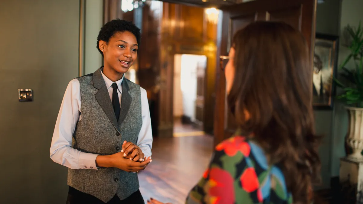 Hotel employee speaks with a guest, whose back is to the camera