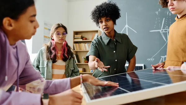 Teacher showing solar panel to a group of students.