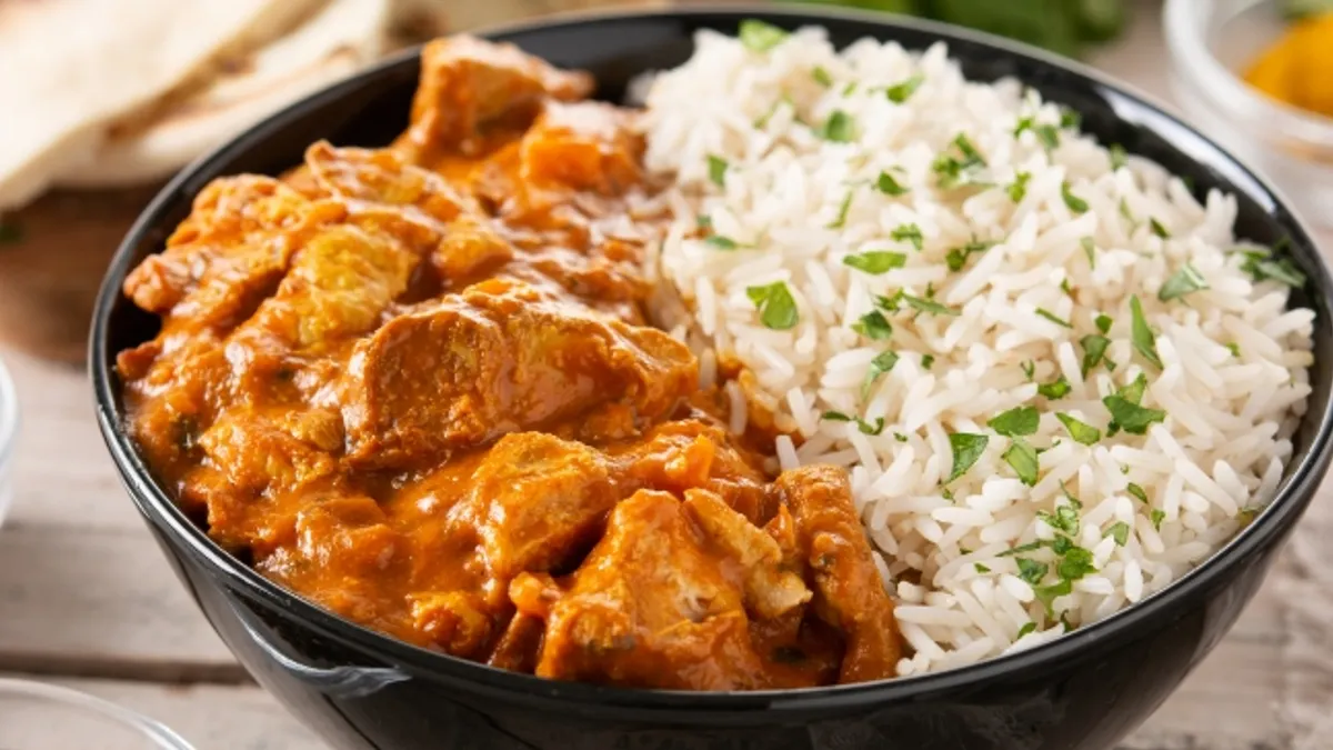 Indian butter chicken in black bowl on wooden table