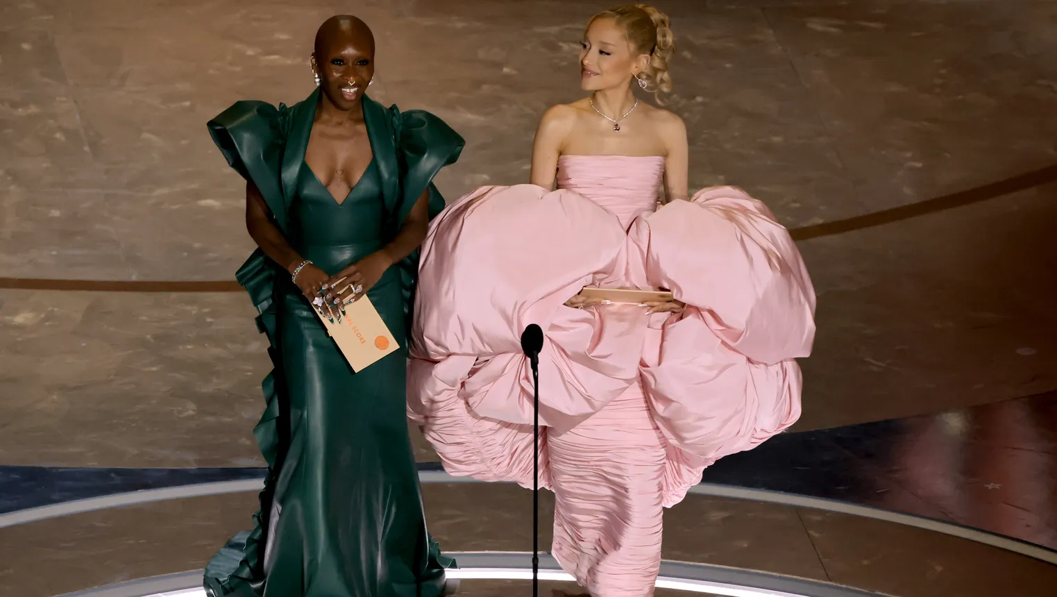 Cynthia Erivo in a green gown and Ariana Grande in a pink gown.