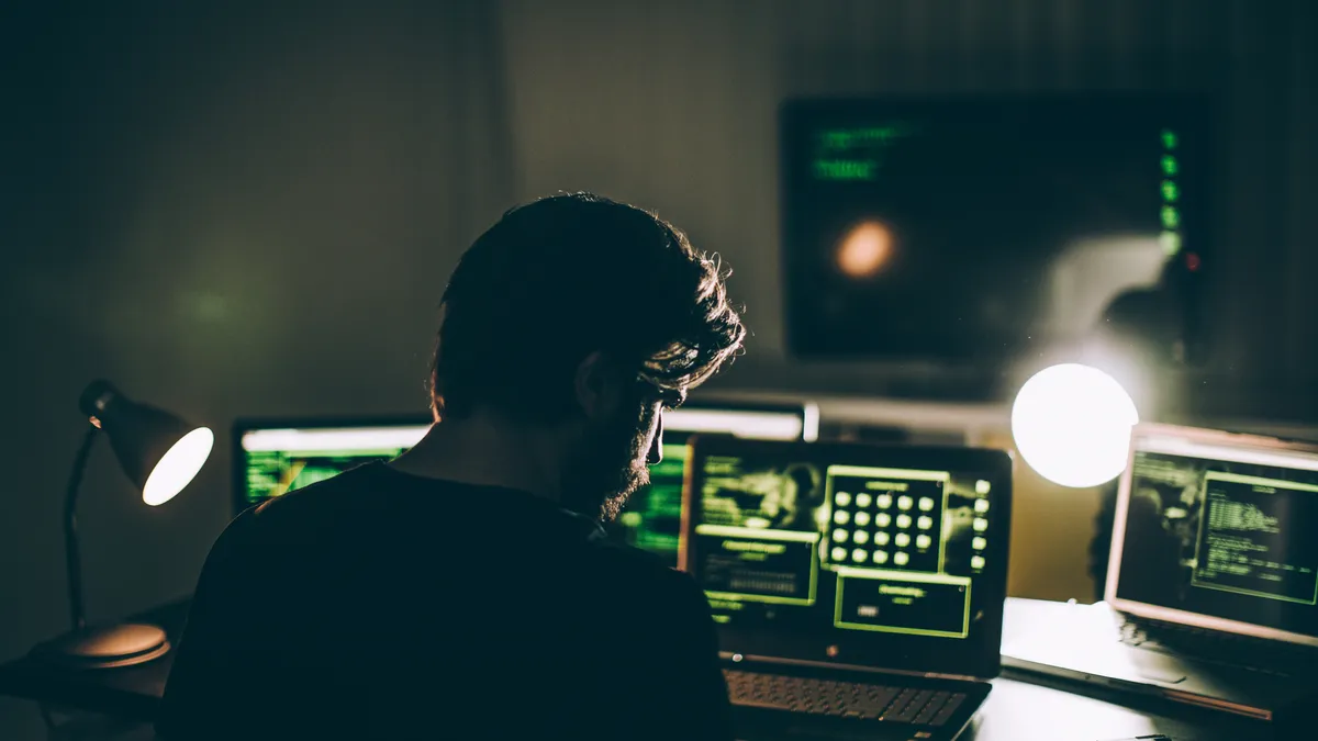 A man faces multiple computer screens.