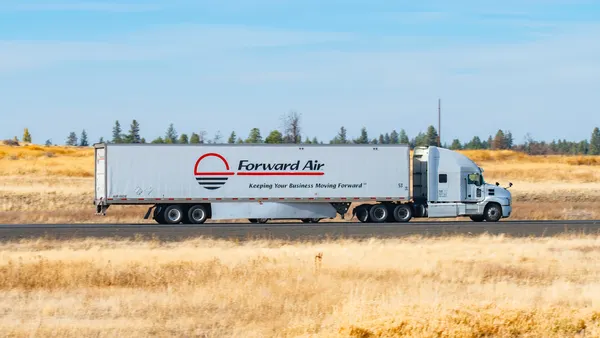 A Forward Air semi-truck driving on a rural section of Interstate 90 in eastern Washington state with some trees in the background.
