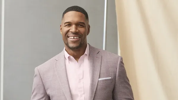 Michael Strahan modeling a dusty rose colored blazer and pink shirt from his brand