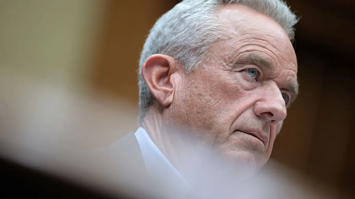A close-up of a person in a suit looking off to the right.