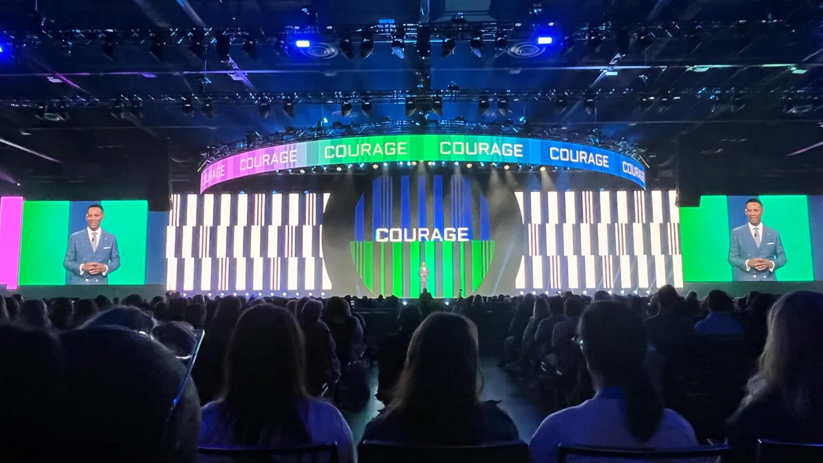 The word "courage" flashes on stage as SHRM's Johnny Taylor speaks at SHRM26 in Orlando, Fla.