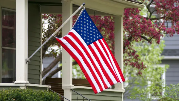 An American flag flying on a house's flagpole.