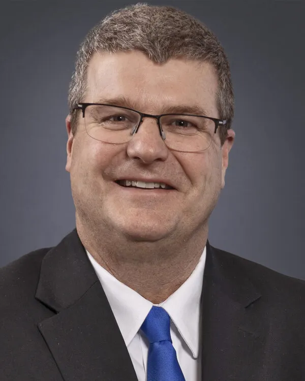 Dennis Shaffer poses for a photo wearing a suit and tie