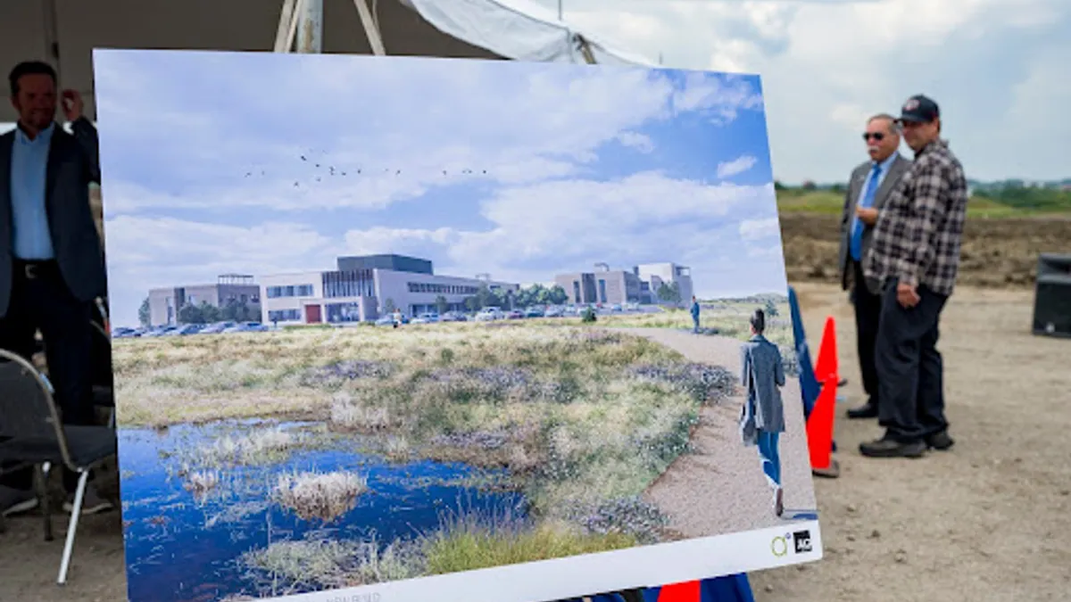 A rendering of a future hospital is propped on an easel at a groundbreaking ceremony.