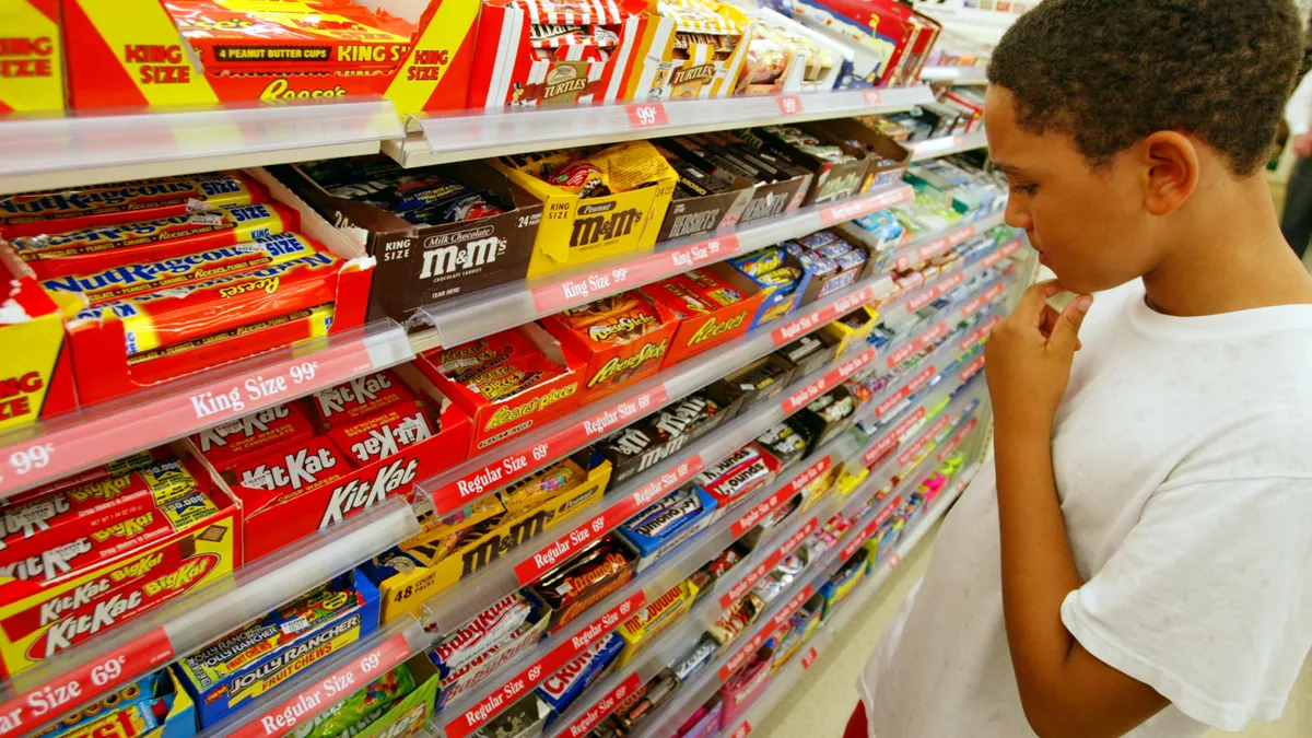 A child looks at several choices in the candy aisle of a store.