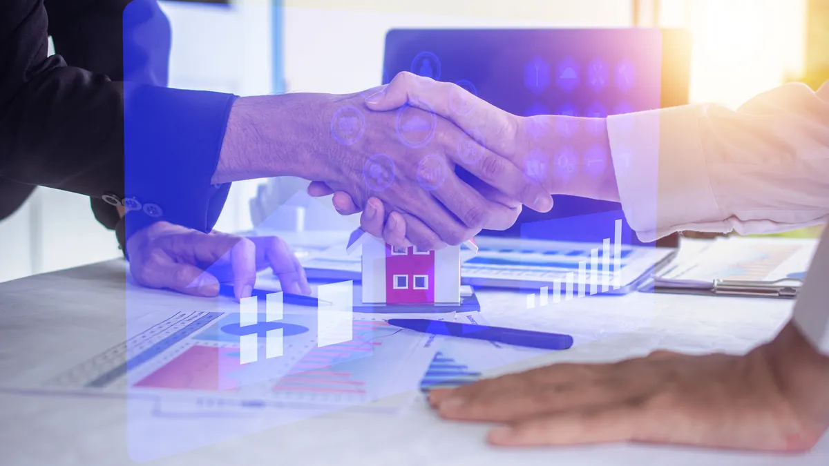 Closeup of a handshake with architectural drawings in the background.