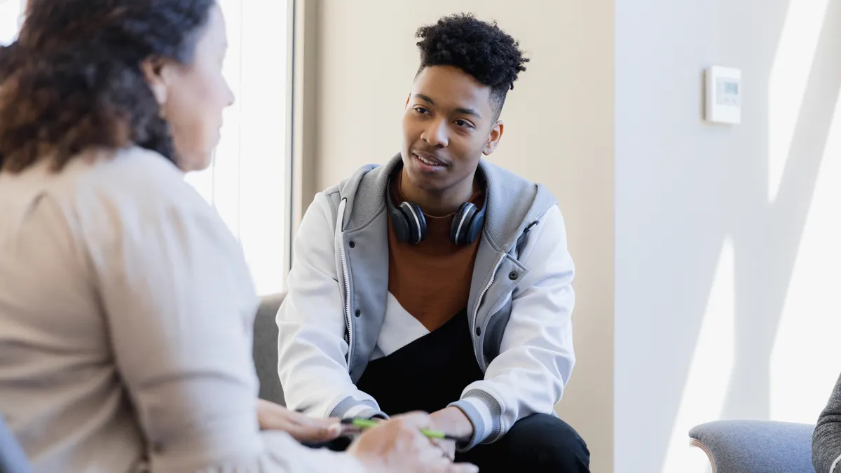 A female counselor talks to a young man.