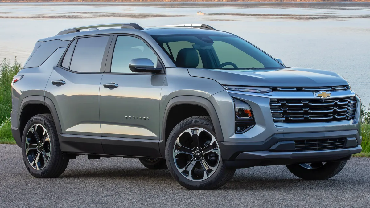 Front 3/4 view of a 2025 Chevrolet Equinox LT in Sterling Gray Metallic parked outdoors near a large body of water.