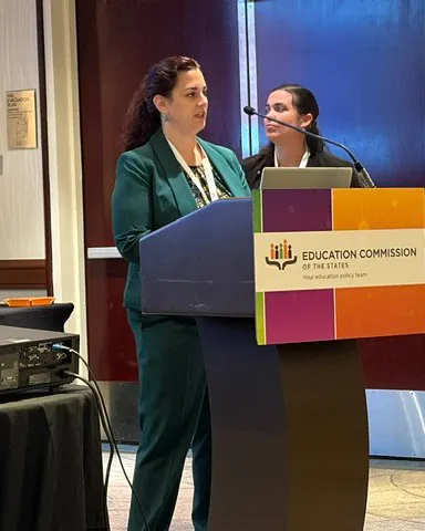 Two people are standing behind a podium in a room.