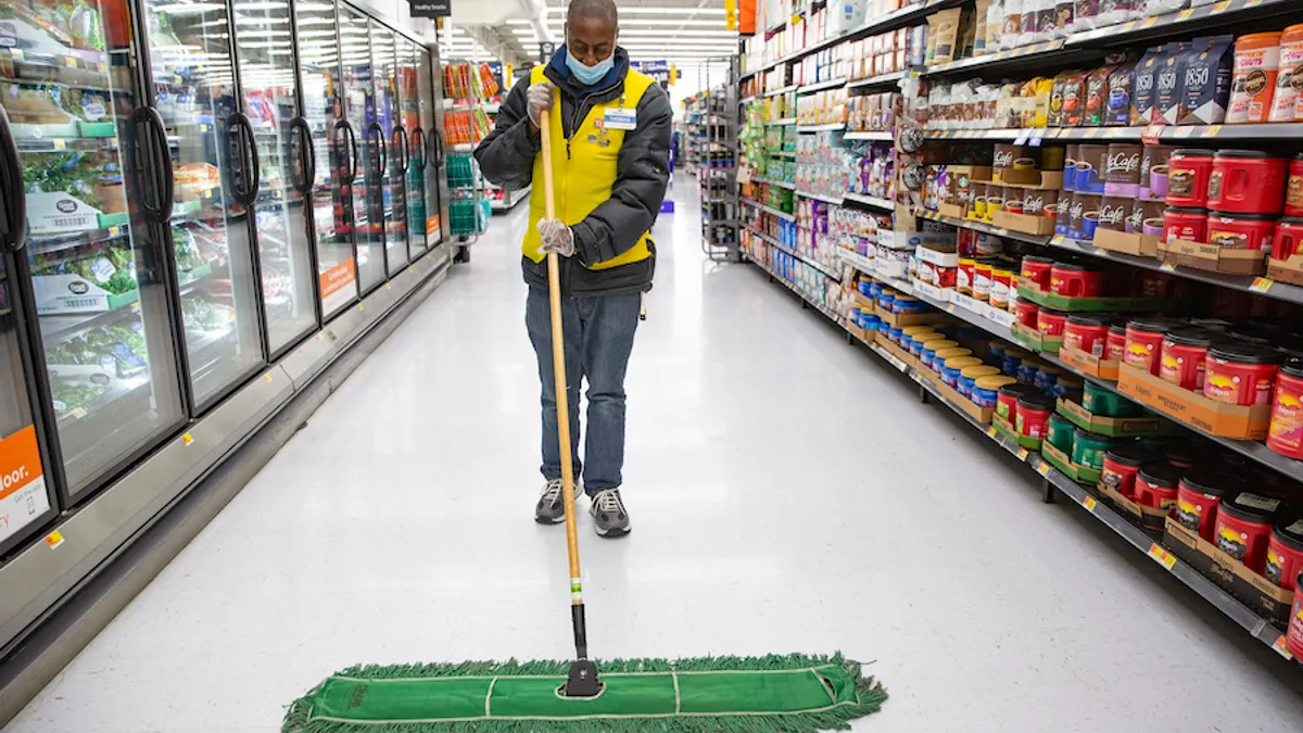 A Walmart employee mops the floor in the grocery aisle.