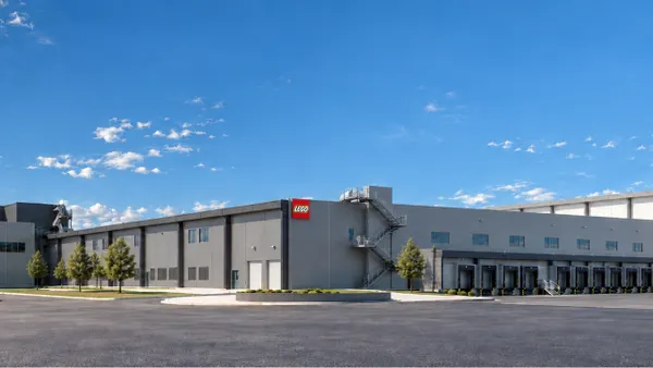 A stone-gray shade building with onyx shade lining, with the red, white and yellow Lego logo sign on the side of it.