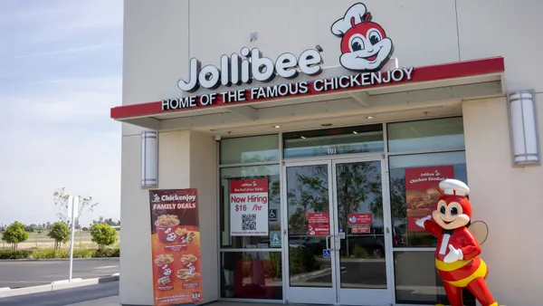 An image of a  white building with signage that says "Jollibee Home of the Famous ChickenJoy"