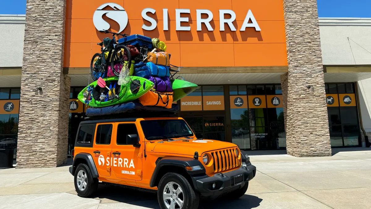 An orange Sierra-branded vehicle with outdoors products stacked on top.