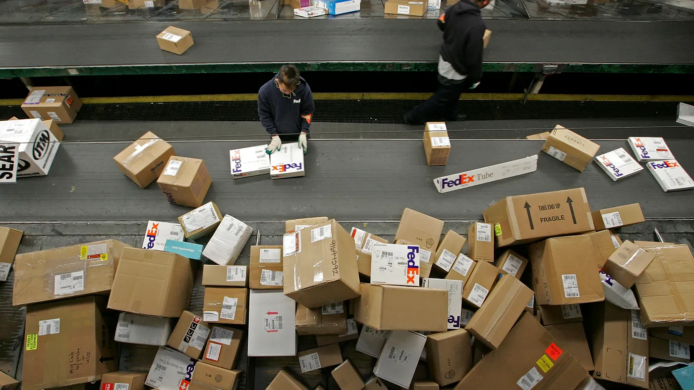 A FedEx worker sorts packages being unloaded from a truck on a conveyor belt at the FedEx Oakland Airport sort facility.