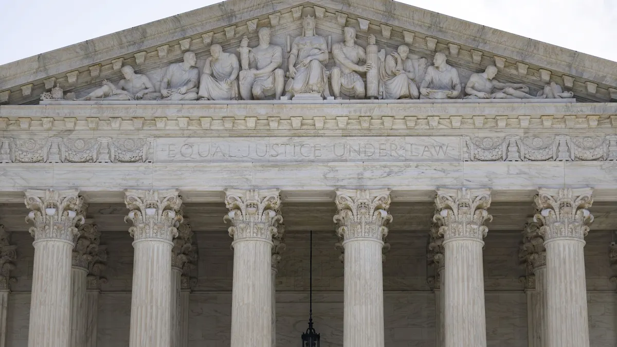 A view of the top of a building exterior that has columns and the phrase "equal justice under law" written above.