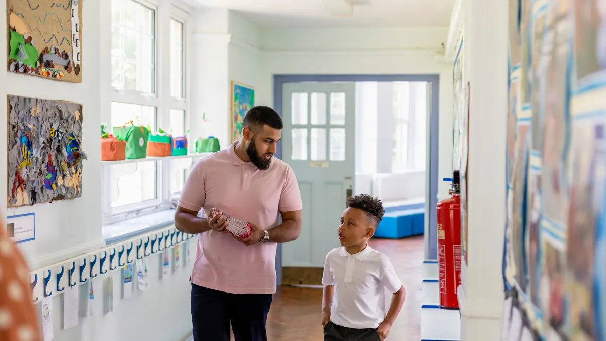 A school employee walks alongside a student in a school hallway