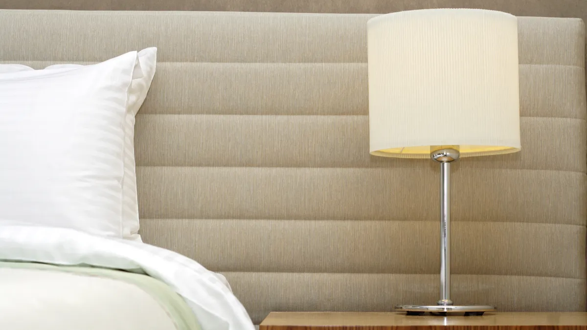 Closeup of a hotel bed and nightstand with a lamp