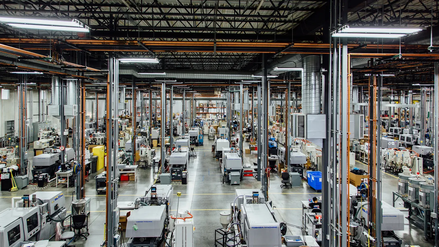 A wide shot of a factory with machinery, pipelines, and other technology sources on a gray hardwood floor