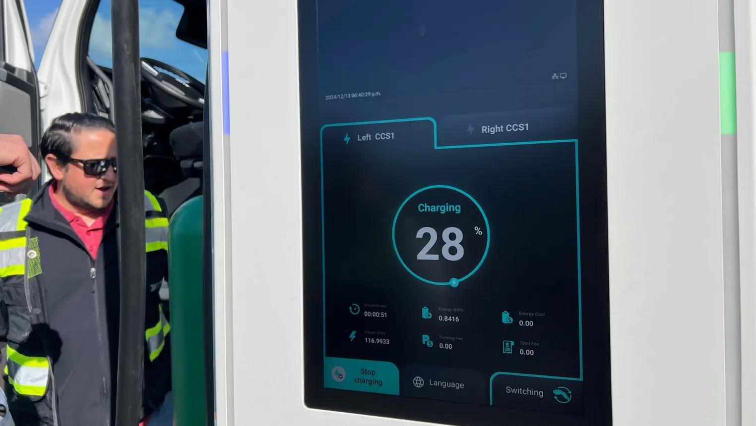 A digital display reads Charging 28% and other technical details at a Forum Mobility EV truck charging site.