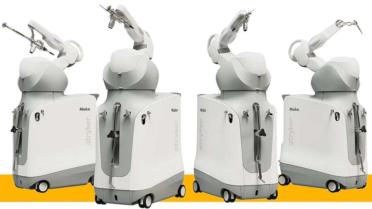 Four robots side by side with a single arm have different instruments attached to the end.