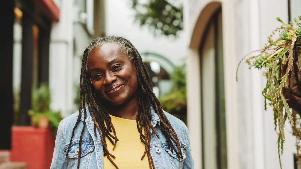 An older Black woman with dreads smiles