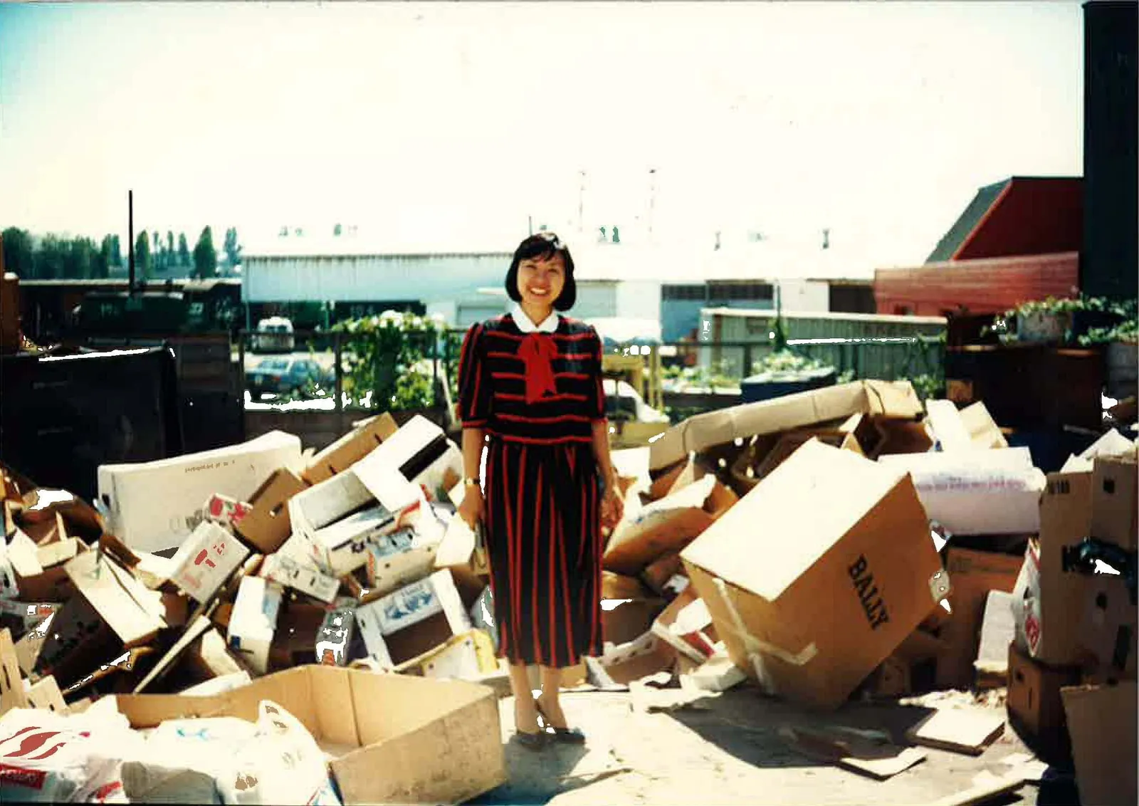 A woman stands amid piles of boxes and paper.