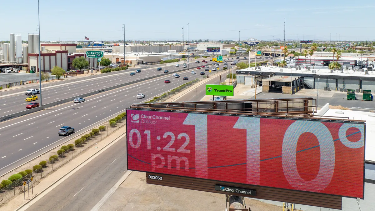 Aerial shot of a highway alongside a billboard that reads 1:22 p.m., 110 degrees F.