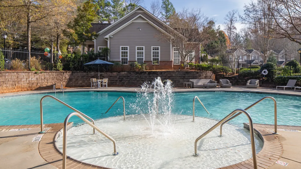 A pool with garden-style apartments in the background