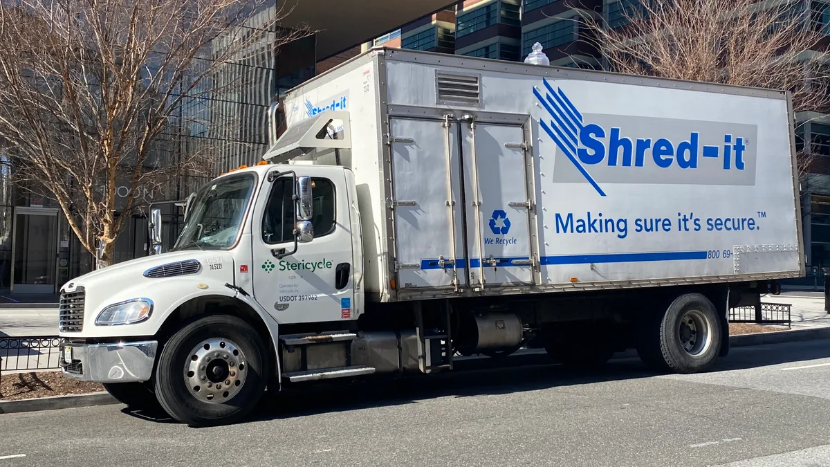 A white Stericycle truck is parked on the street