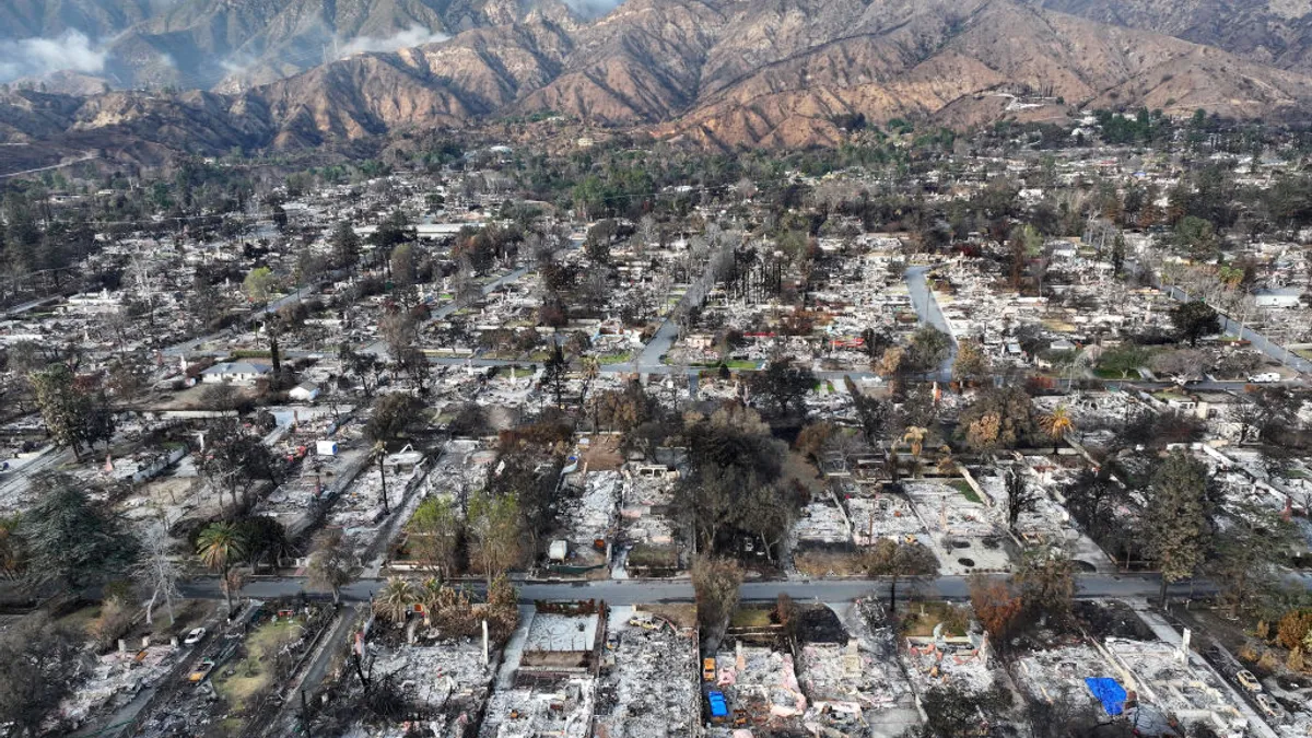 An aerial view of a burned-out neighborhood with mountains in the background.