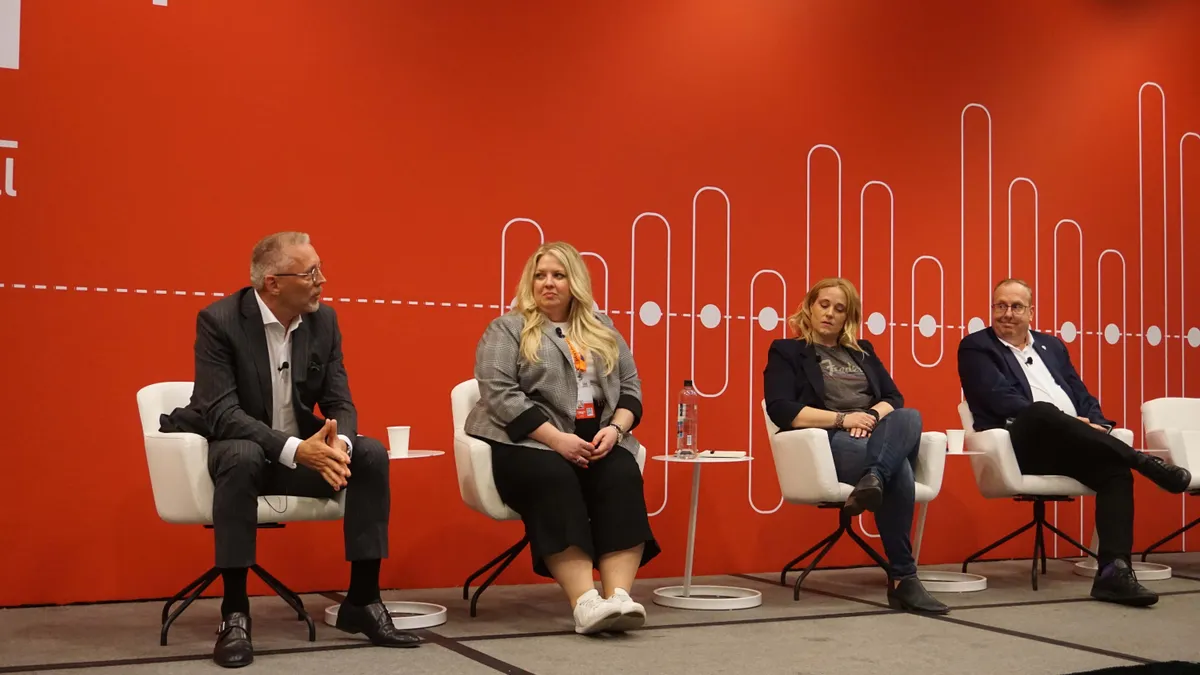 Four people sit on a stage as speakers during a conference panel