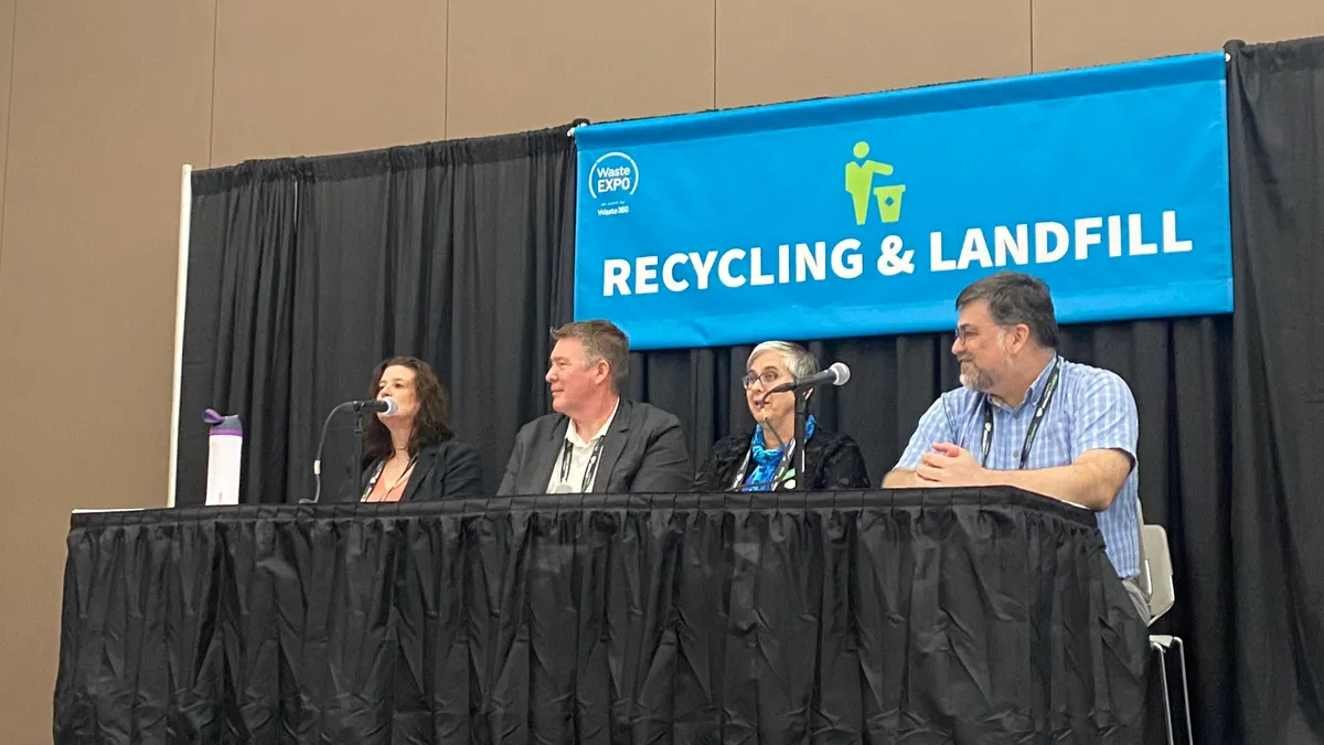 People sit at a table speaking into microphones at WasteExpo