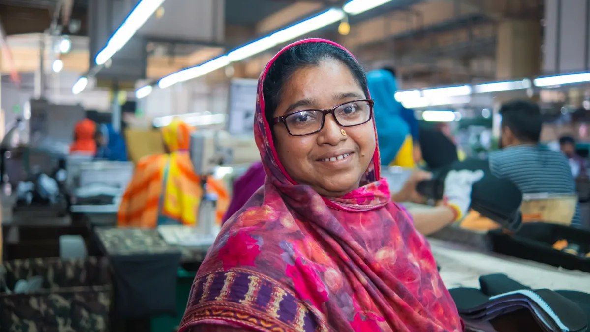 A person is pictured in a garment factory wearing eyeglasses.