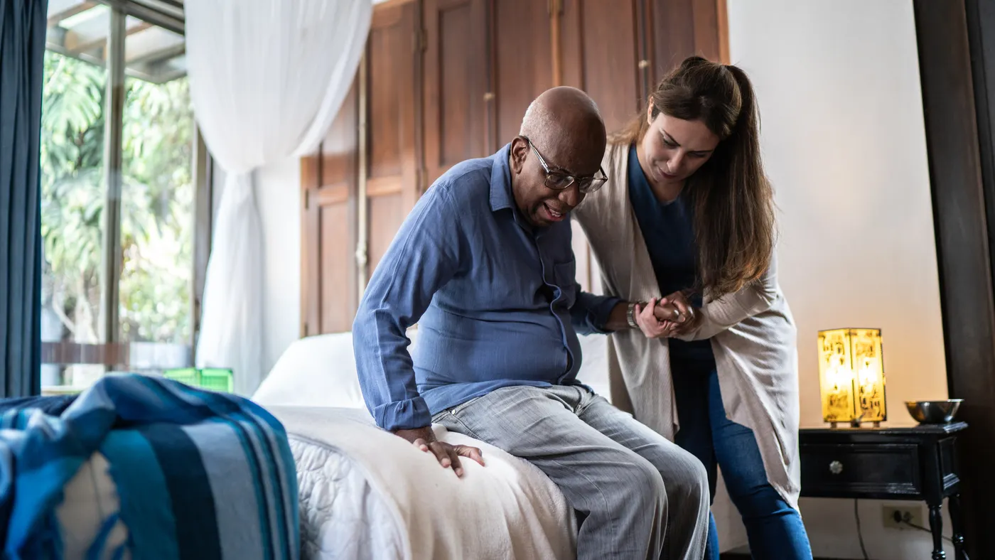 A home health aide assists a man.