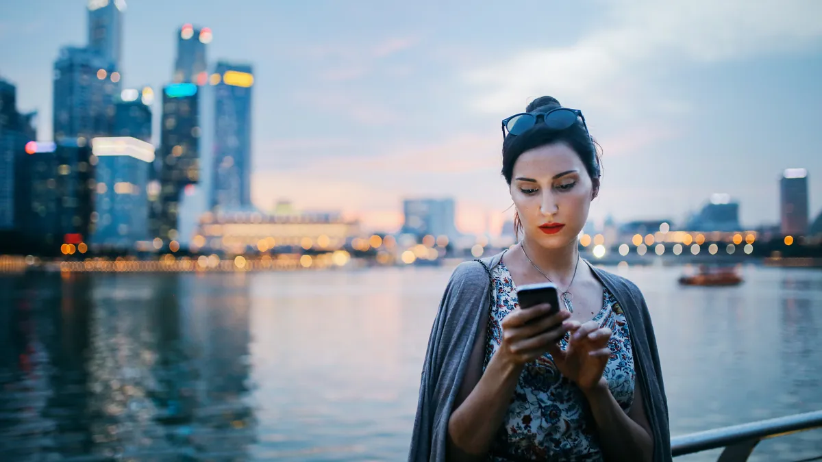 Young fashionable tourist woman in Singapore checking out her smartphone