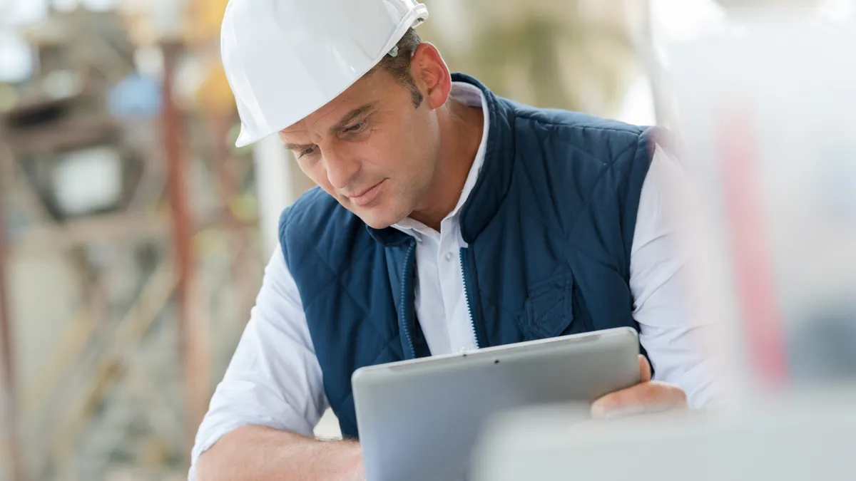 Male architect wearing hard hat reviewing blueprints