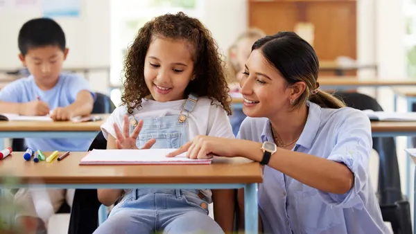 Teacher kneeling by her little female student